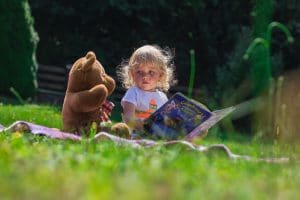 girl sitting beside a teddy bear